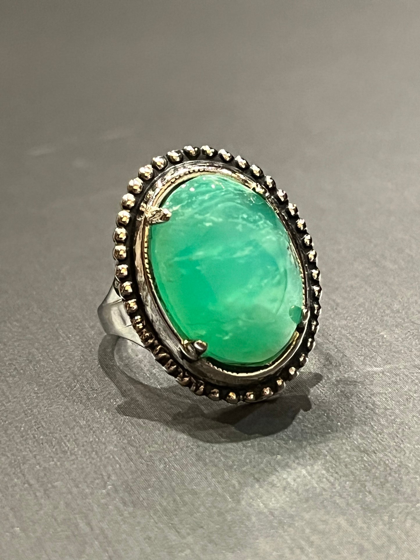 Bright green Chrysoprase set in an antique silver ring setting. This unique piece of jewelry is authentic Alaska Native art created by an enrolled member of an Alaska Native tribe. Certified Silver Hand and Made in Alaska jewelry.